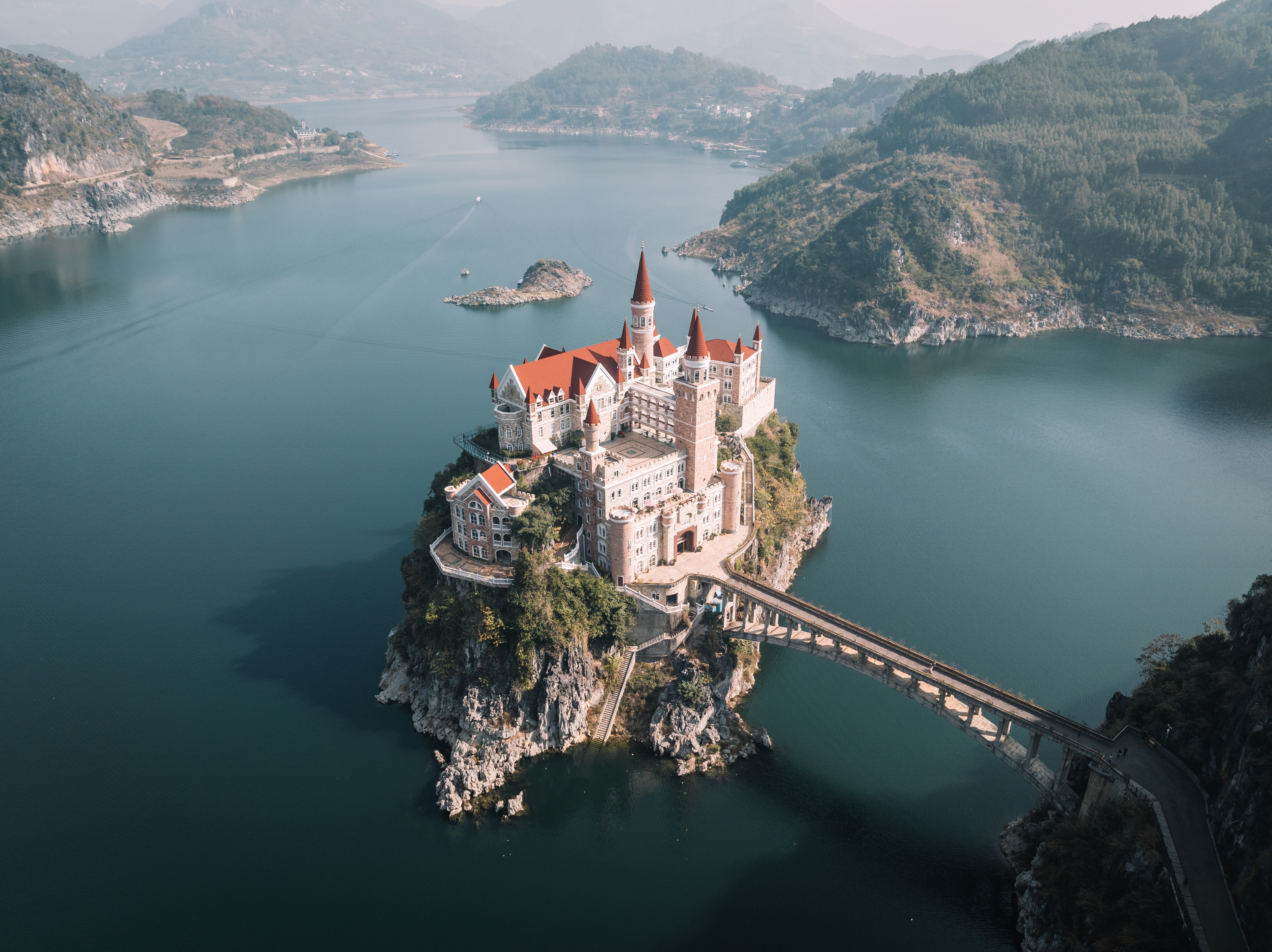 Castle on a rock island surrounded by lake and mountains
