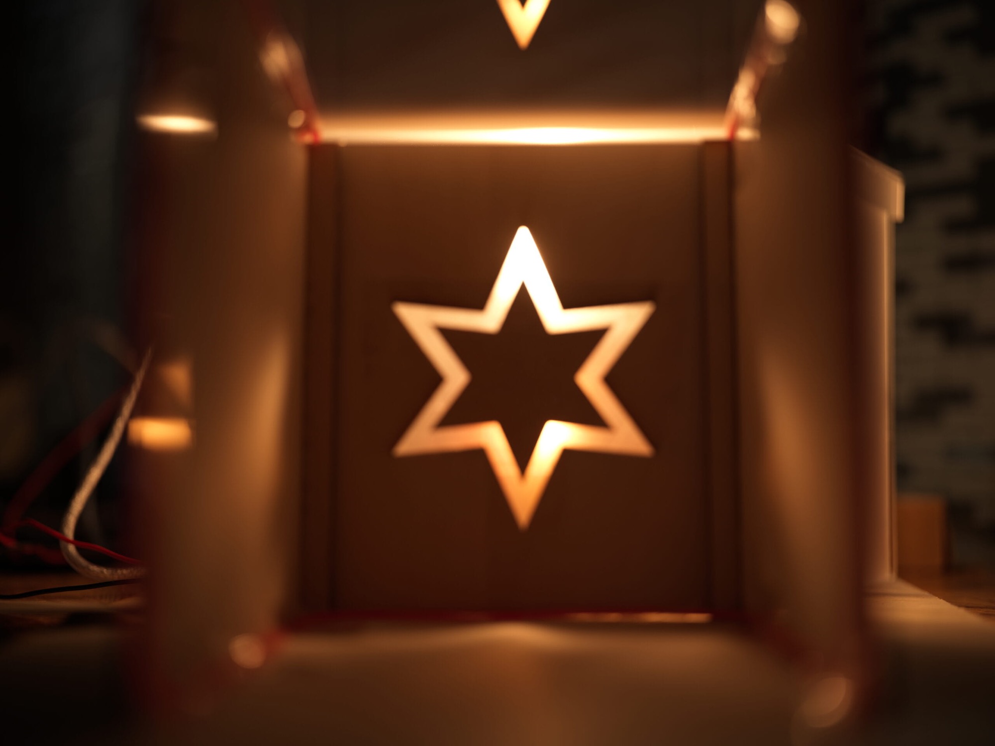 A glowing hexagram of light cast through a cut panel inside the model