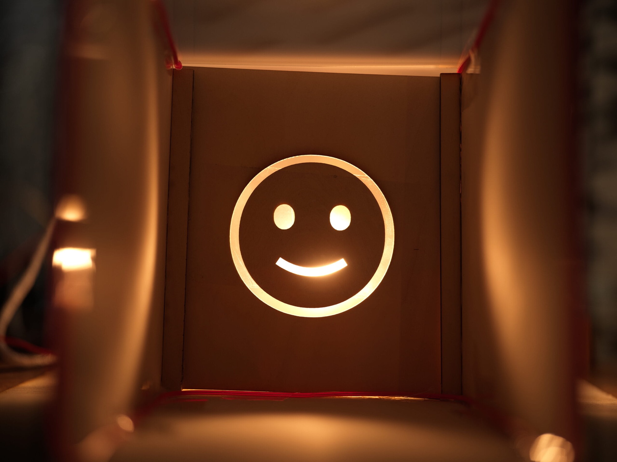 A glowing smiley face of light cast through a cut panel inside the model
