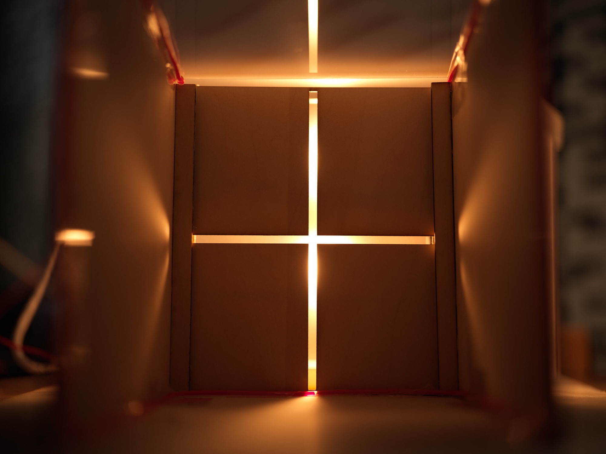 Echoes of Light - a cross of warm light glowing through layered wooden panels inside the model