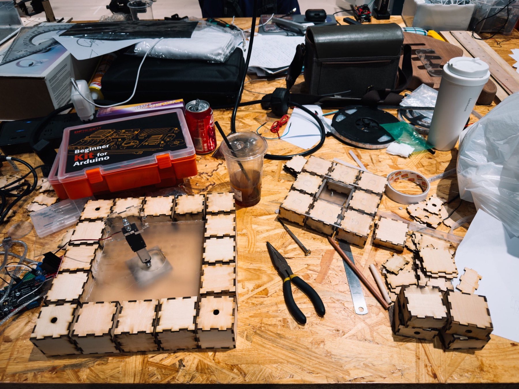 Workbench covered with laser-cut plywood modules, pliers and tape during assembly