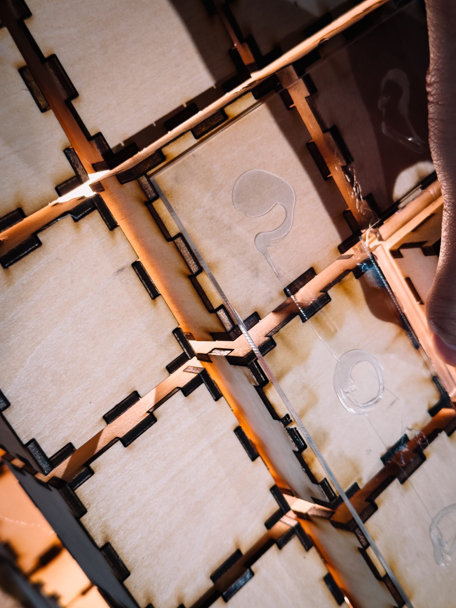 Close-up of etched transparent acrylic tiles set among the wooden blocks, lit warmly from within