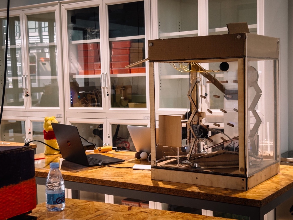 GPS Random Scoring Machine - laser-cut pinball tower of chain reactions that assigns grades by chance