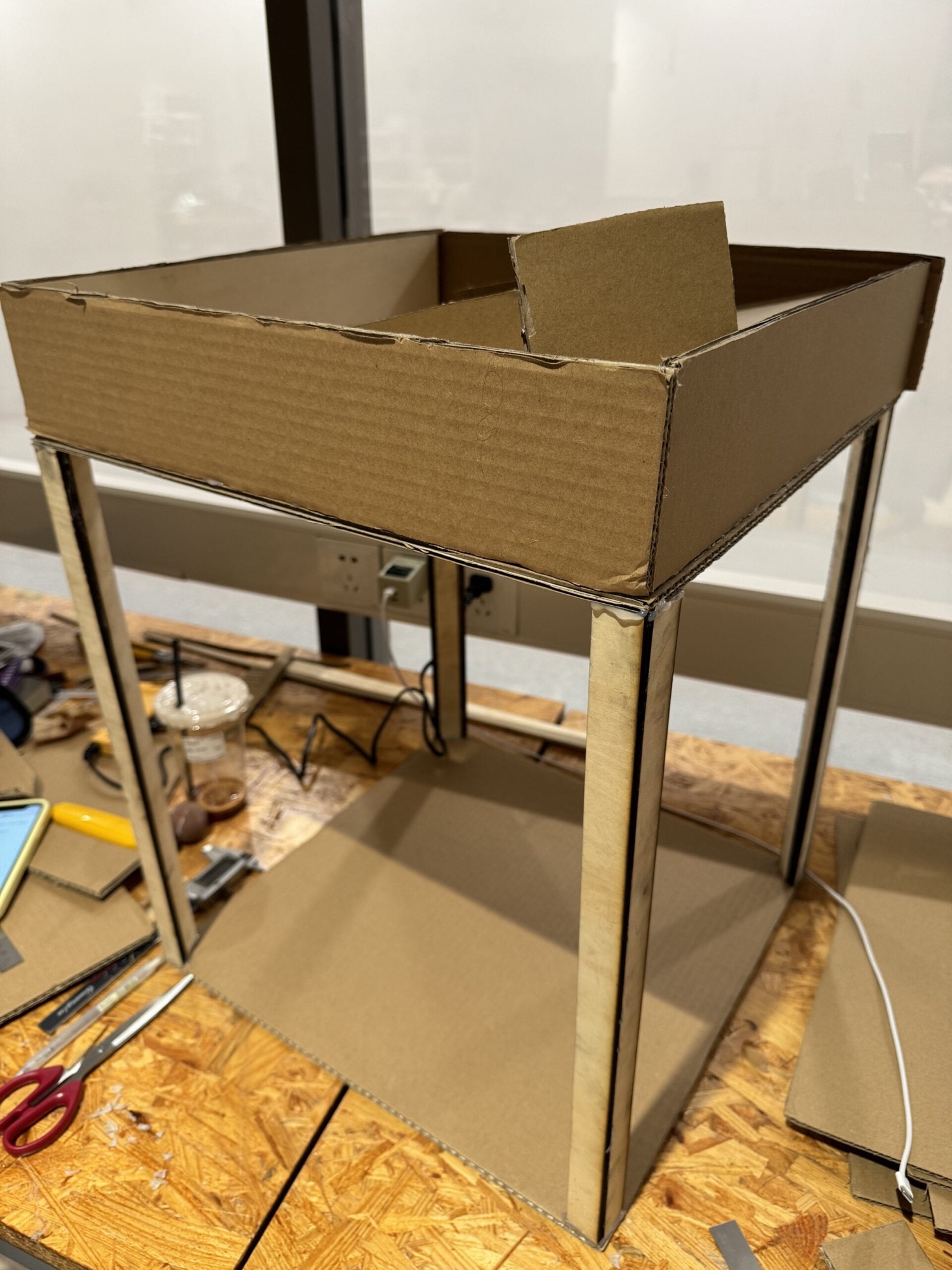 The tall cardboard and wood frame of the machine during assembly