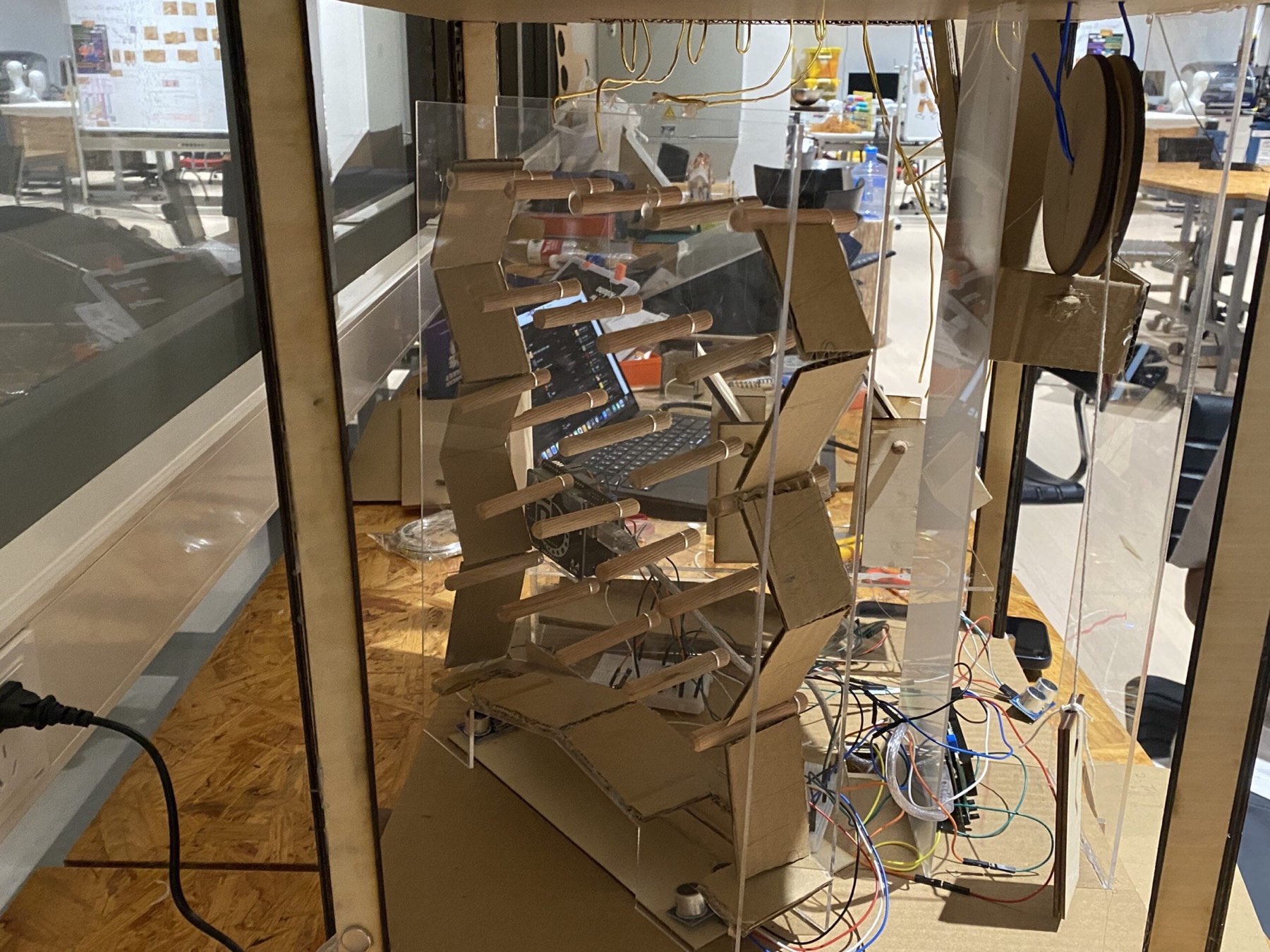 Cardboard chain-reaction relays, acrylic panels, and wiring inside the machine