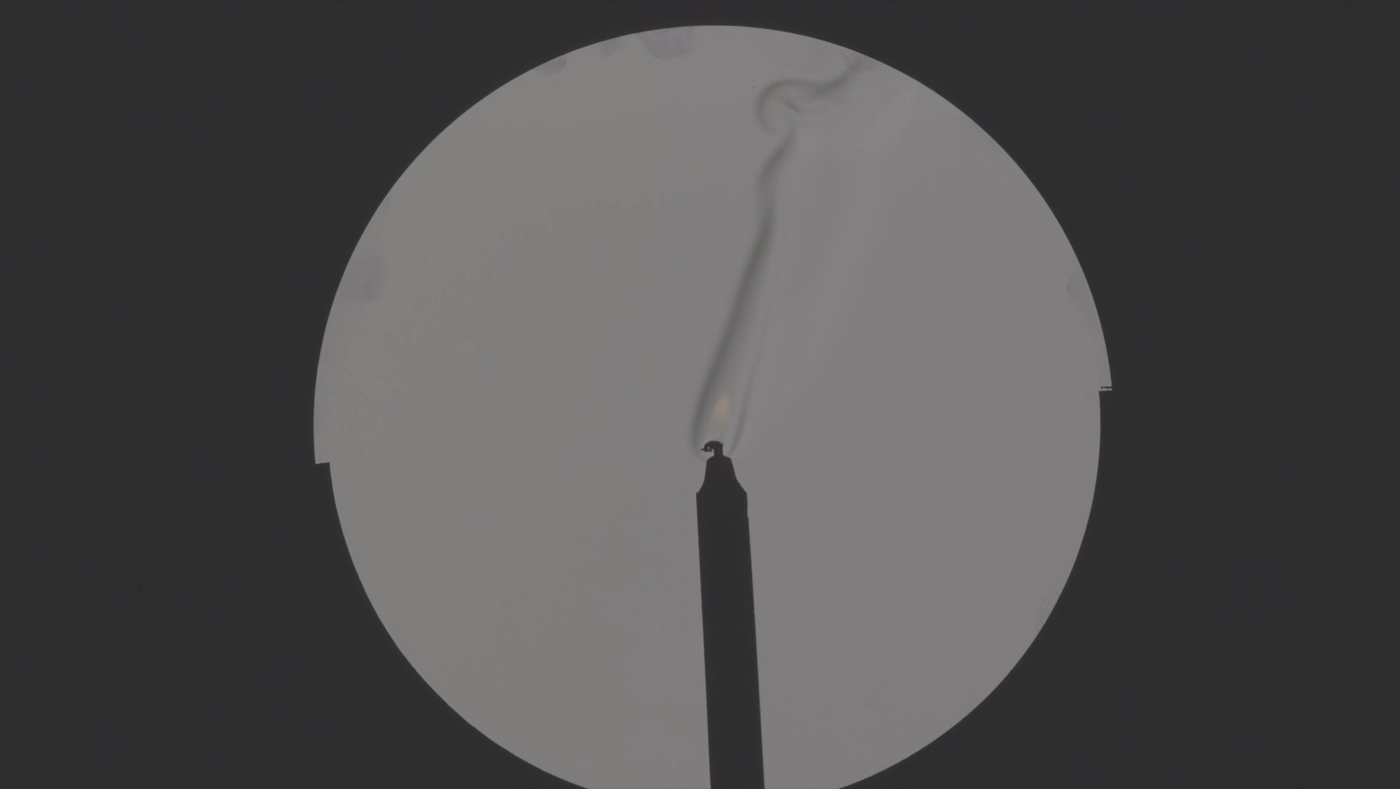 Invisible Currents - warm air rising from a candle flame made visible as a pale plume inside the mirror's circle of light