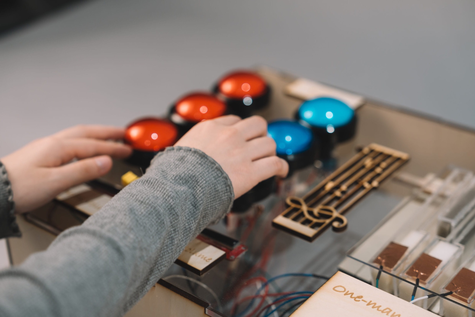 Hands pressing the red and blue arcade buttons of the beat section