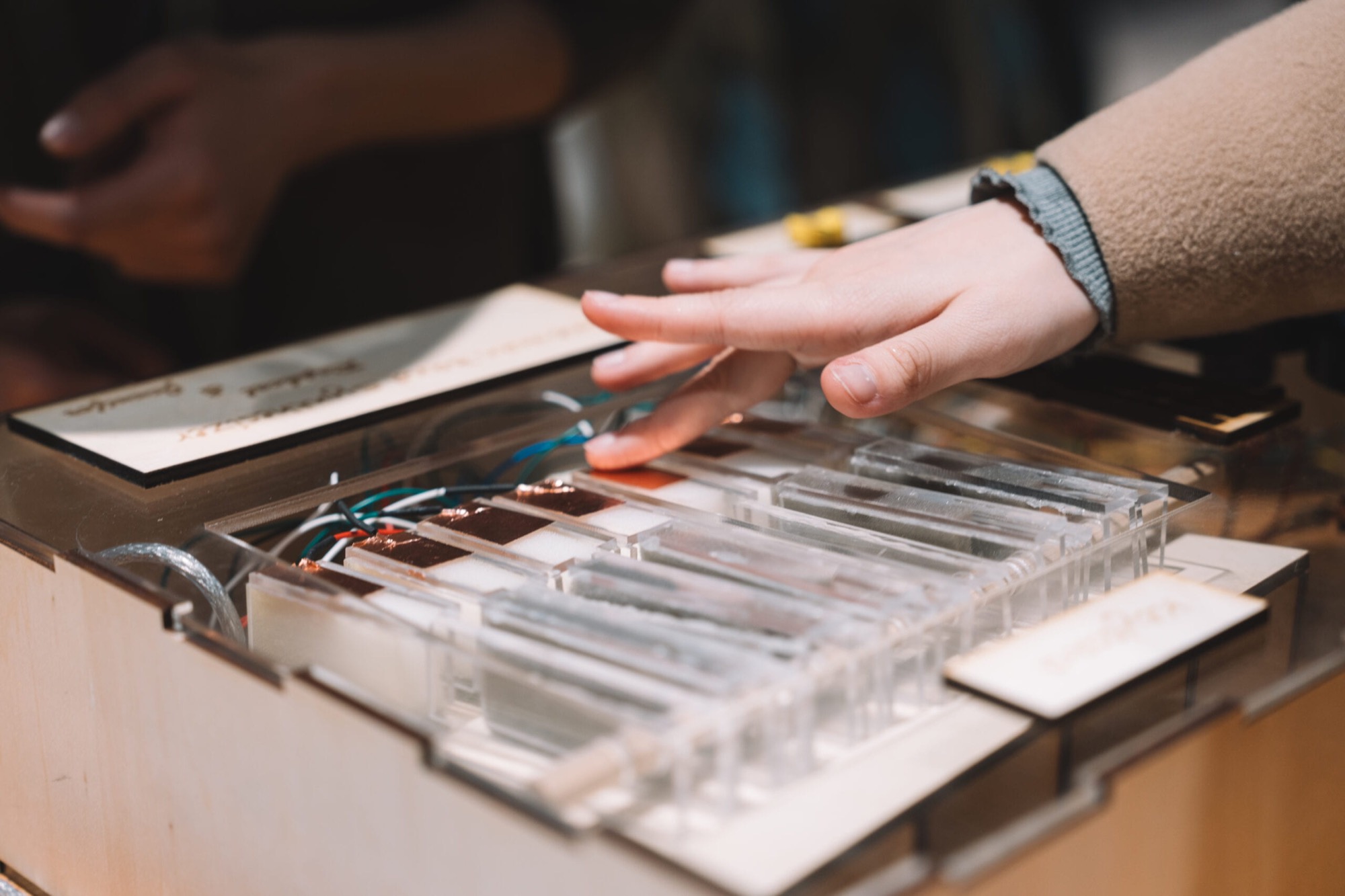 A visitor's hand pressing the transparent acrylic keys