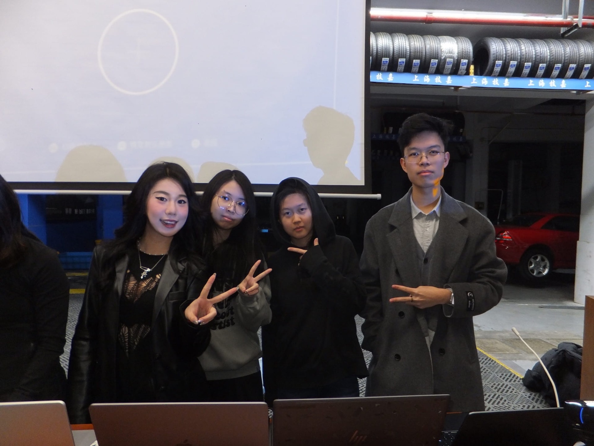 The four team members posing in front of the projection screen in the garage venue after the performance