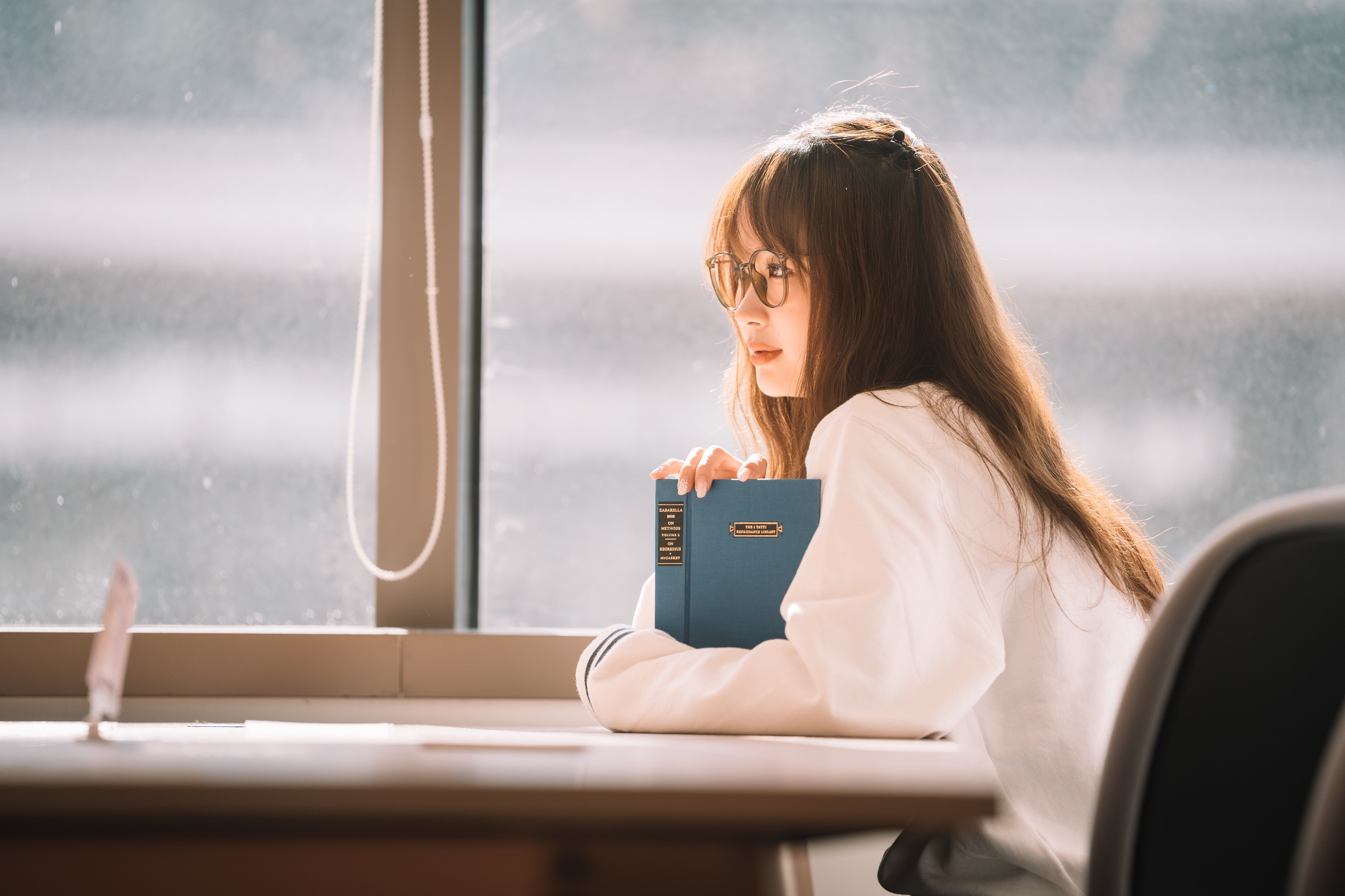 By the library window with a blue clothbound book, Shanghai, 2023