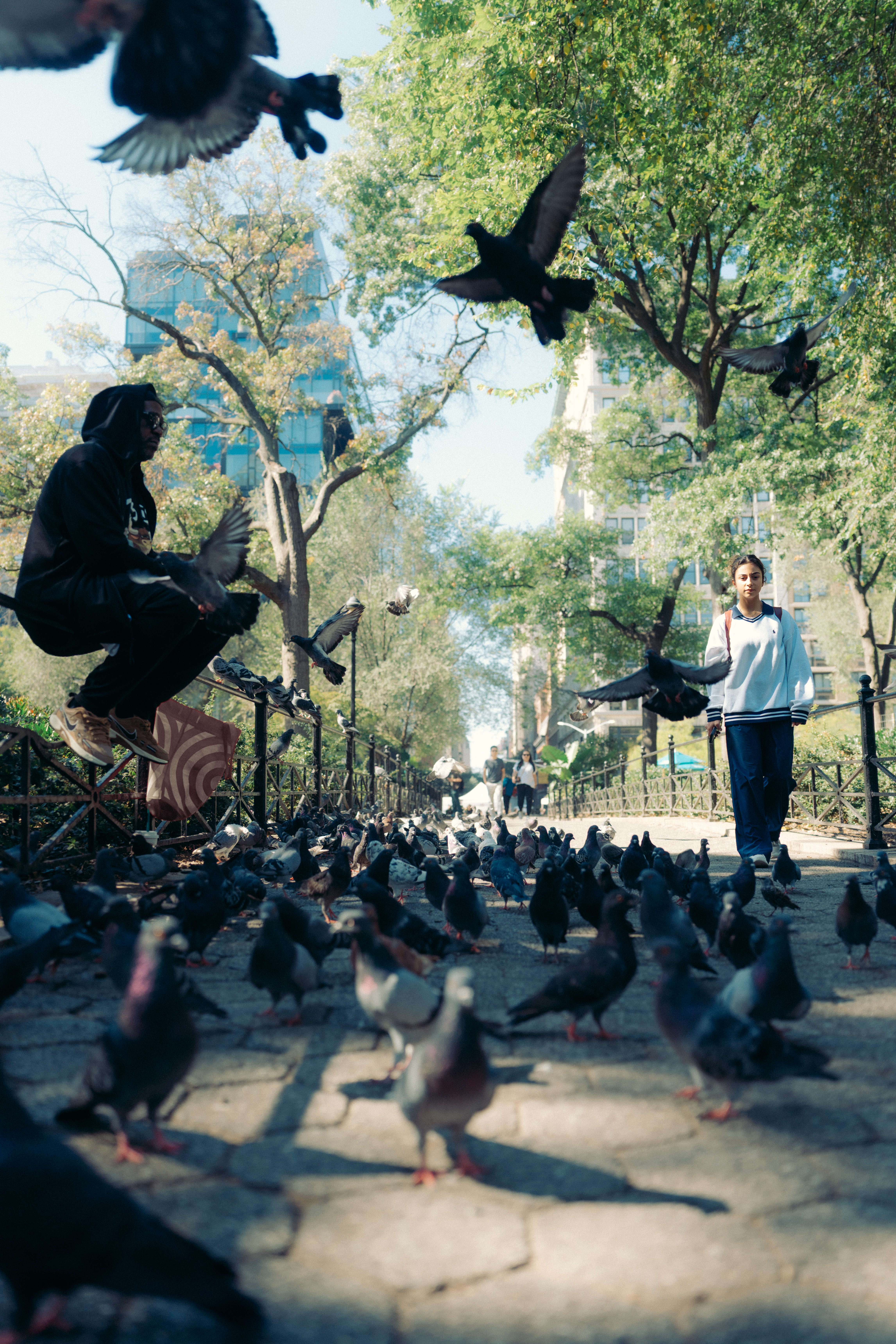Man on railing, schoolgirl walking, pigeons between