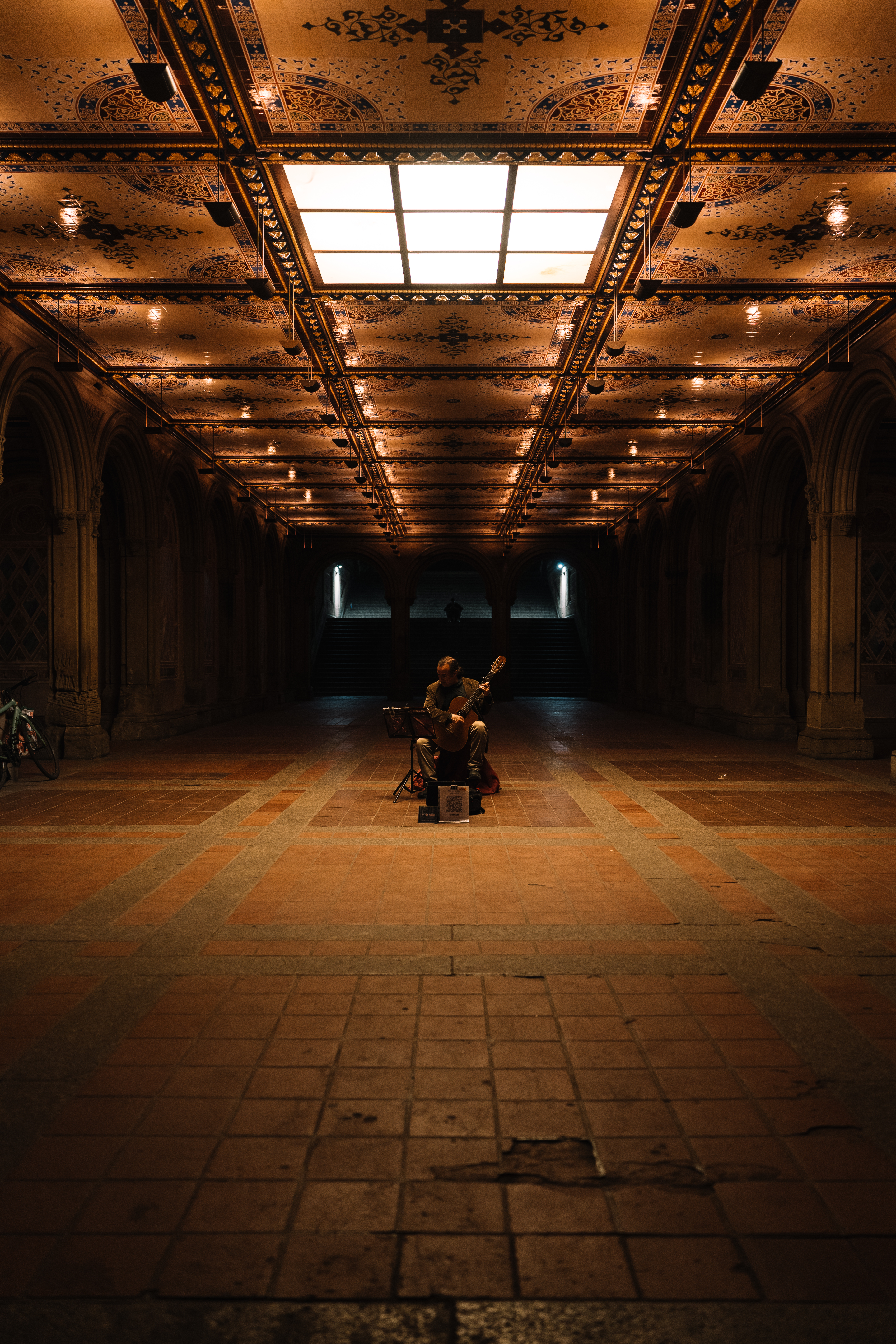 Man playing classical guitar at night under Bethesda arches