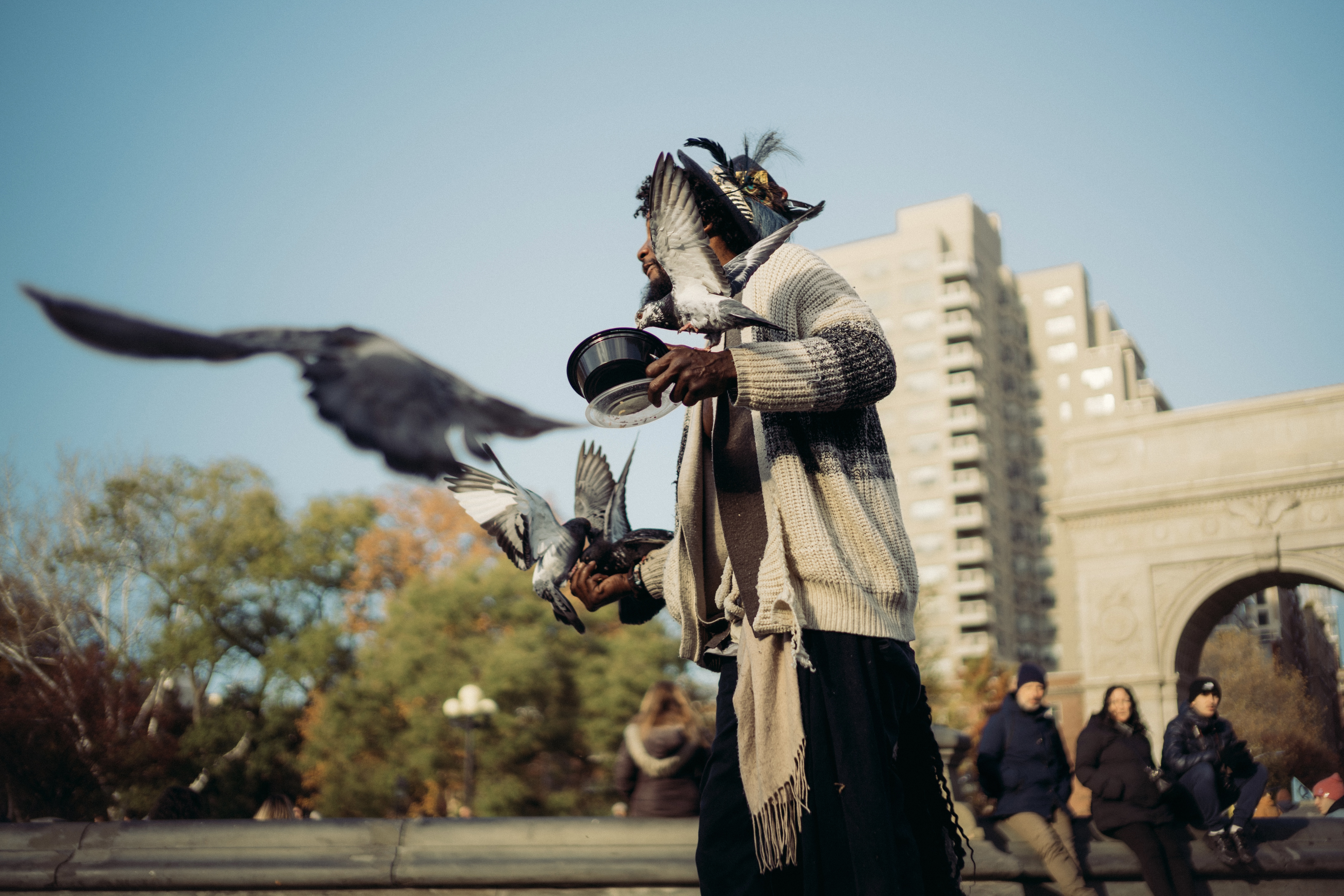 Man in tattered clothes feeding pigeons